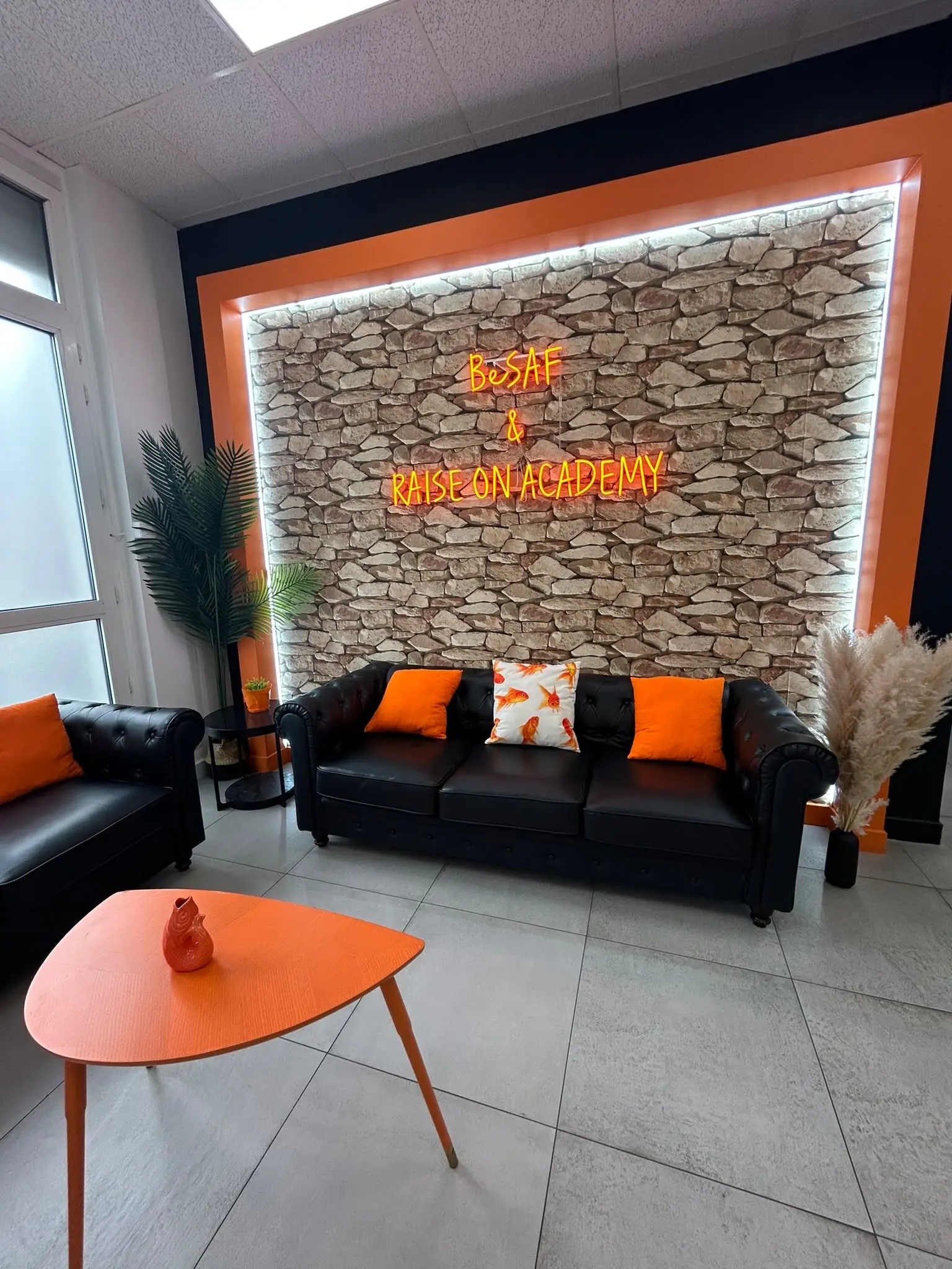 Le lounge BeSAF et Raise On Academy, enseigne néon orange sur mur de pierre